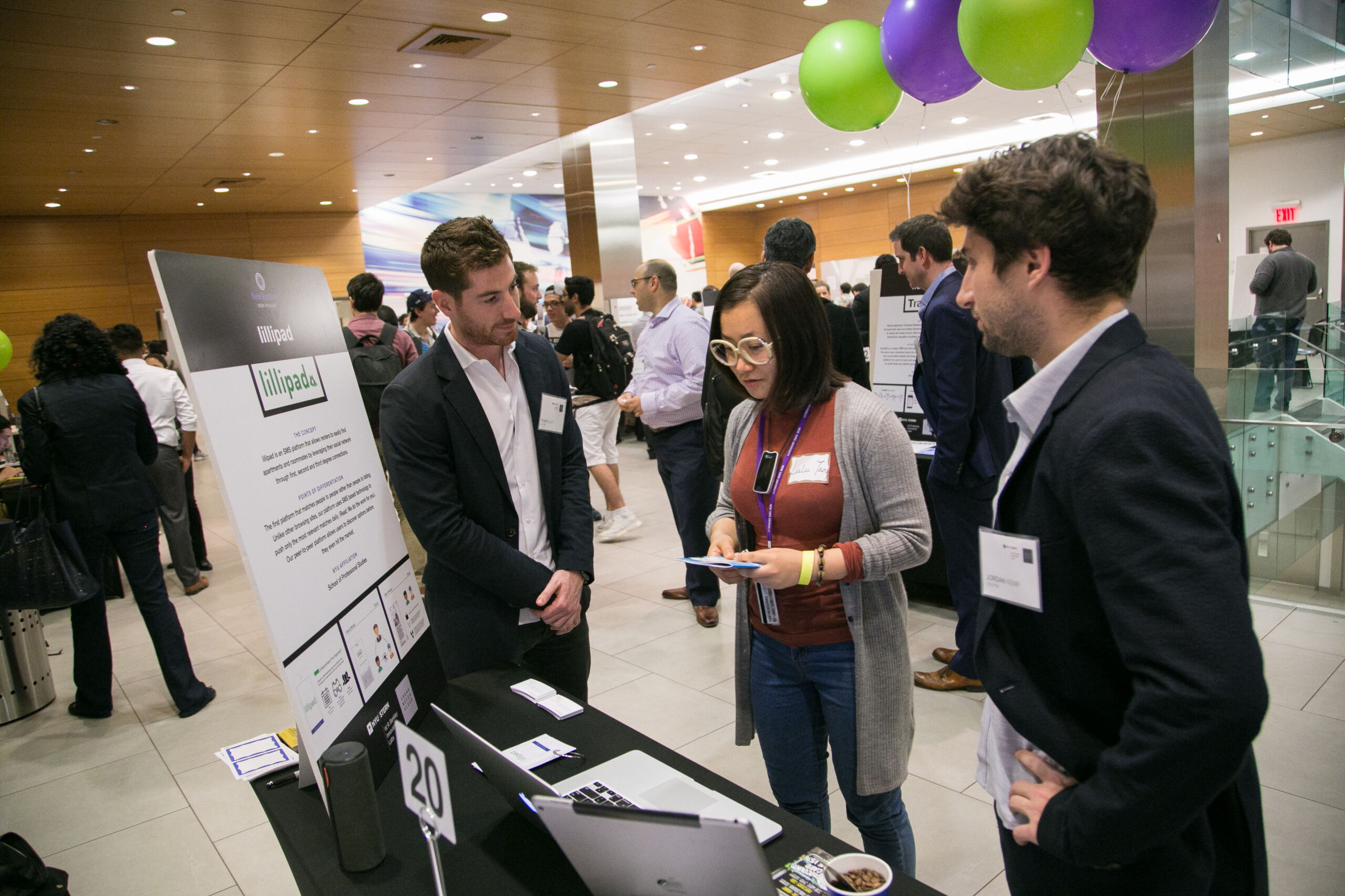 Event guests engaging with a startup at their presentation booth at the Venture Showcase.
