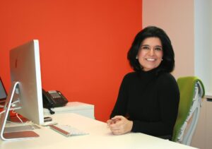 Shabnam Rezaei sitting at a desk smiling at the camera